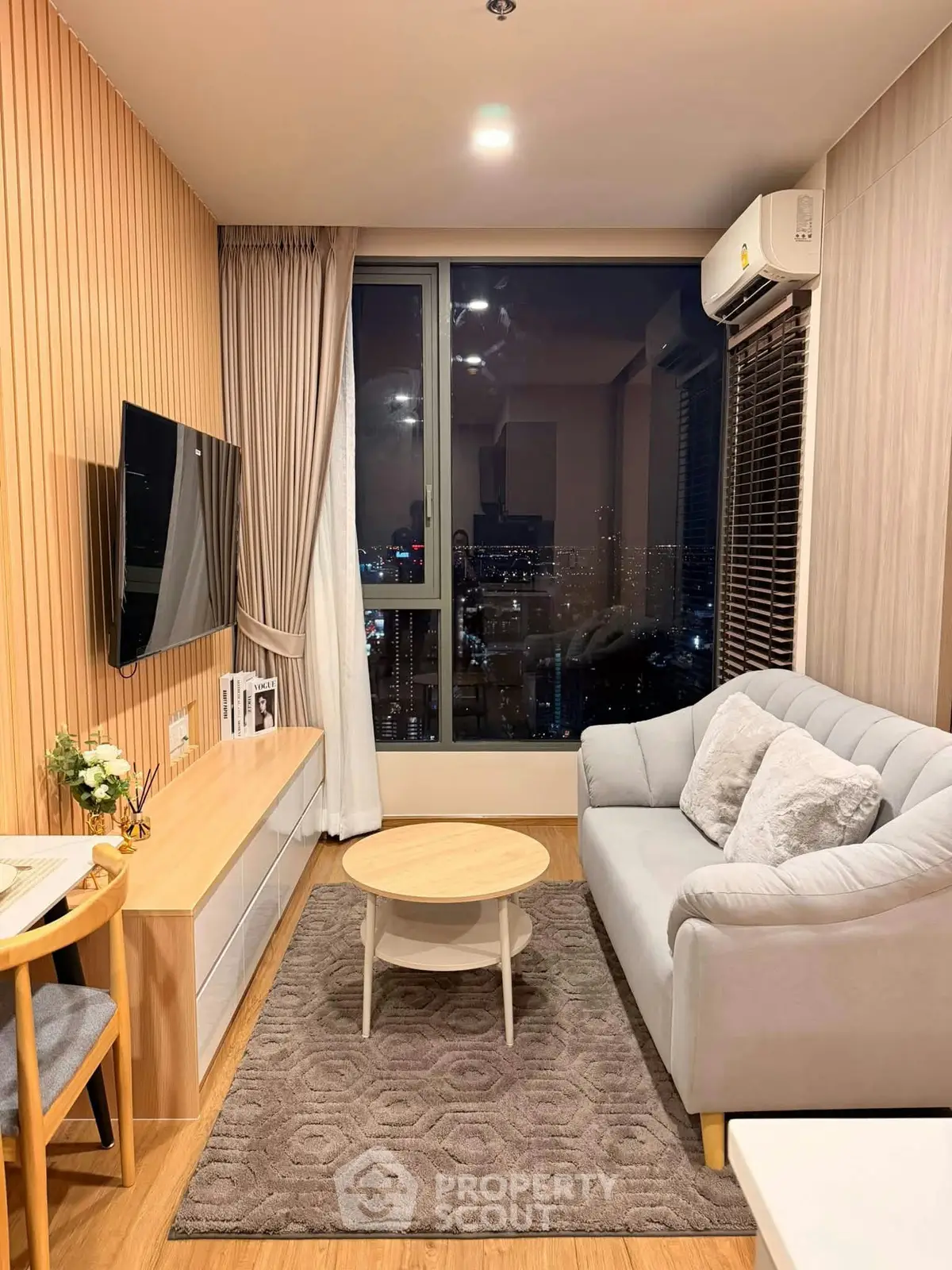 Modern living room with city view, cozy sofa, and stylish decor in high-rise apartment.