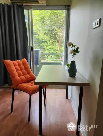 Cozy study nook with vibrant orange chair and serene garden view