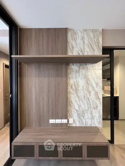 Modern interior with wood paneling and marble accents, featuring built-in shelving and electrical outlets.