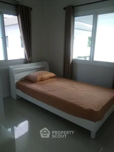 Cozy bedroom with single bed and large windows offering natural light in modern home.
