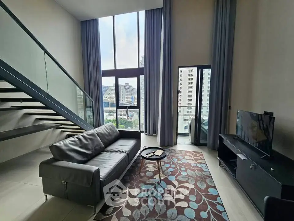 Spacious modern living room with high ceilings and city view, featuring sleek staircase and stylish decor.