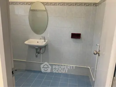 Simple bathroom with oval mirror and blue tiled floor