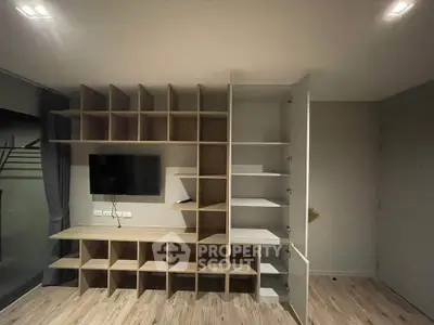Modern living room with custom shelving and mounted TV, showcasing sleek design and ample storage space.