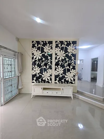 Spacious living room with elegant floral partition and glossy tiled floor