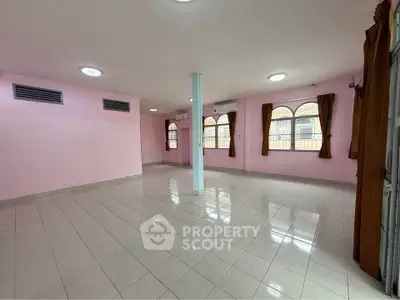 Spacious tiled living room with pink walls and large windows in a modern home.