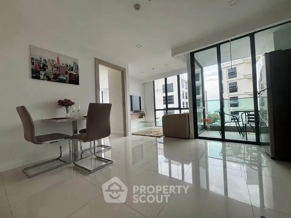 Modern open-plan living room with dining area and balcony access in a stylish apartment.