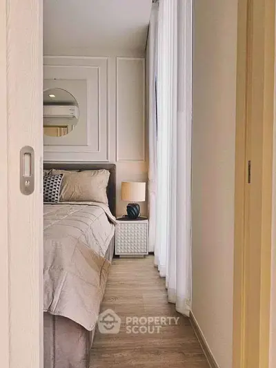Cozy bedroom with elegant decor and natural light through sheer curtains.
