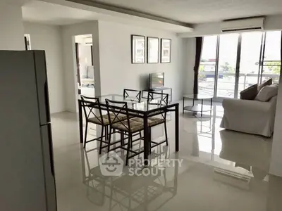 Spacious modern living room with glass dining table and large windows.