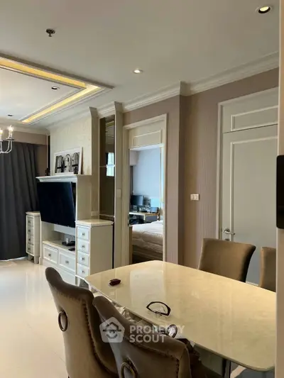 Elegant living room with modern decor and dining area, featuring a wall-mounted TV and stylish furniture.