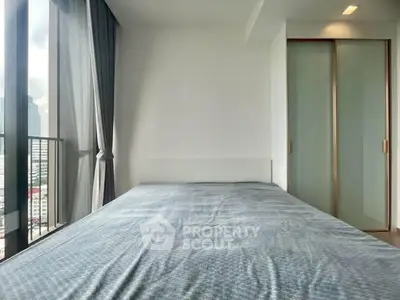 Modern bedroom with large window and city view, featuring sleek sliding closet doors.