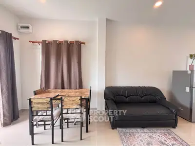 Modern living room with cozy black sofa and wooden dining set, bright and inviting space.