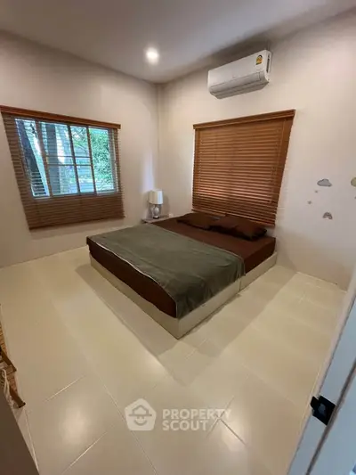 Cozy bedroom with large windows and air conditioning, perfect for relaxation.