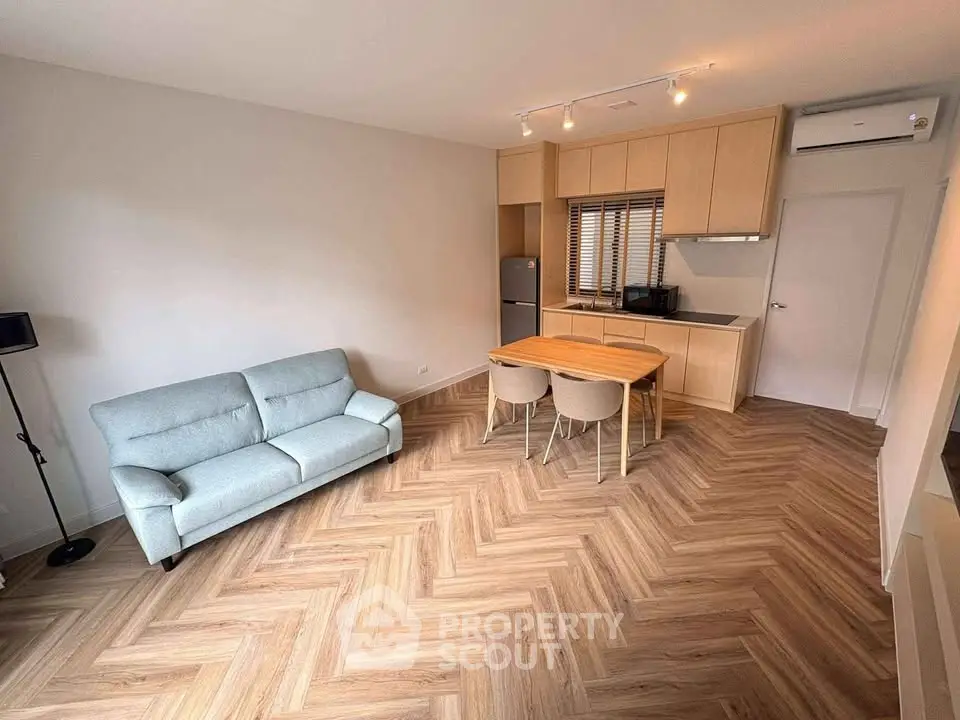 Modern living room with stylish herringbone flooring and open kitchen layout.