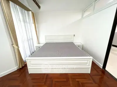 Spacious bedroom with elegant white bed and parquet flooring