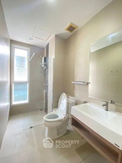 Modern bathroom with sleek fixtures and natural light, featuring a spacious shower and elegant sink.