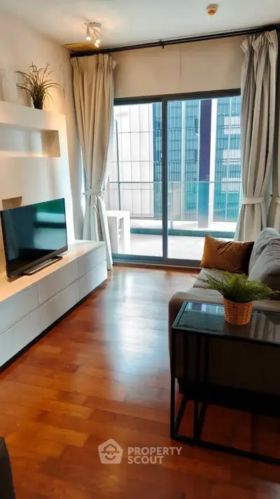 Modern living room with large window and city view, featuring sleek furniture and wooden flooring.