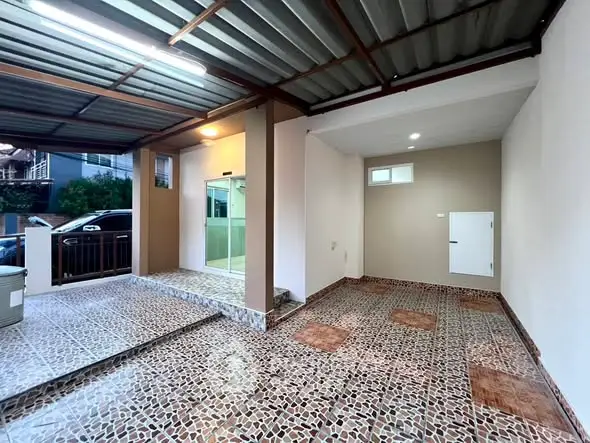 Spacious covered parking area with tiled flooring and modern lighting in a residential property.