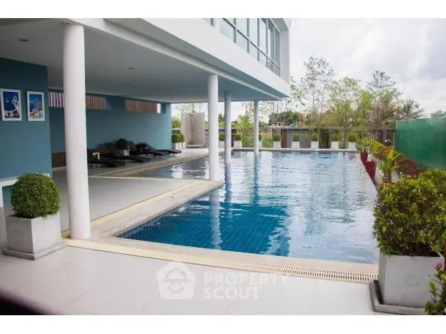 Luxurious modern apartment complex with a stunning outdoor pool and lush greenery.