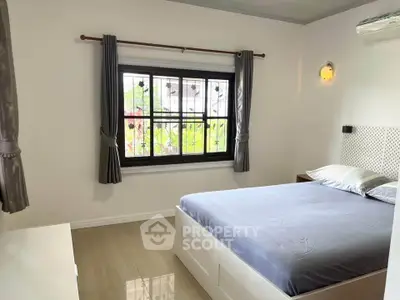 Cozy bedroom with modern decor and large window offering natural light.