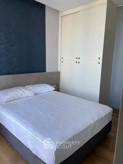 Modern bedroom with stylish blue accent wall and sleek white wardrobe