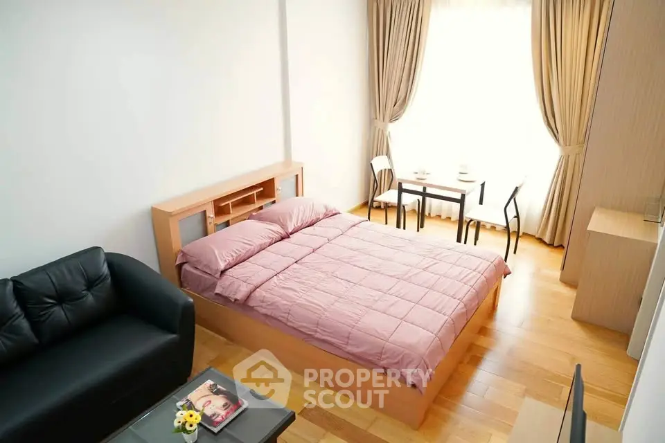 Cozy bedroom with natural light, wooden flooring, and modern furnishings in a stylish apartment.