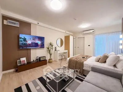 Modern living room with stylish decor, cozy seating, and large TV, perfect for relaxation and entertainment.
