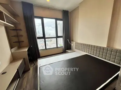 Modern bedroom with city view, featuring sleek furniture and large window for natural light.