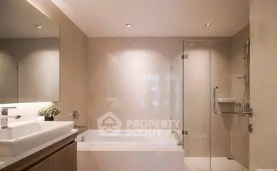Modern bathroom with sleek design featuring bathtub and glass shower enclosure.