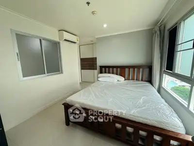 Spacious bedroom with large window and wooden bed frame in modern apartment.