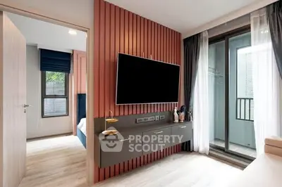 Modern living room with sleek TV setup and balcony access in stylish apartment.