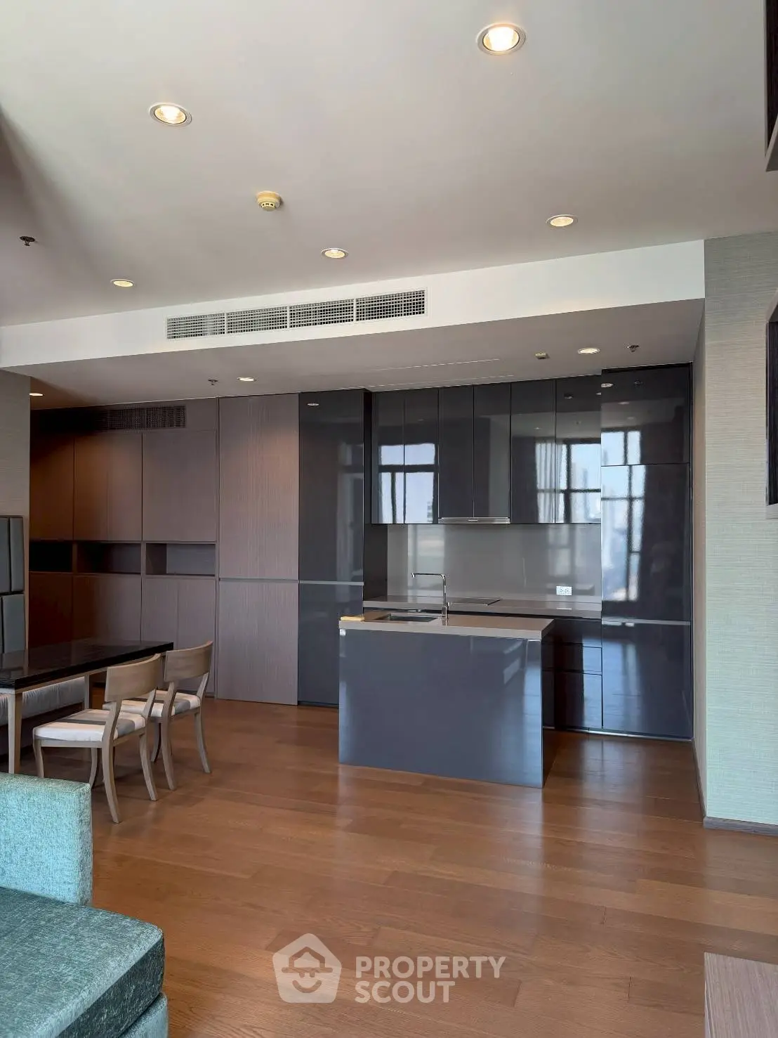 Modern open-layout kitchen with sleek cabinetry and dining area in luxury apartment.