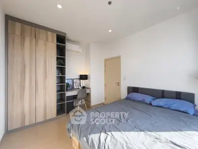 Modern bedroom with built-in wardrobe and study desk, featuring natural light and minimalist design.