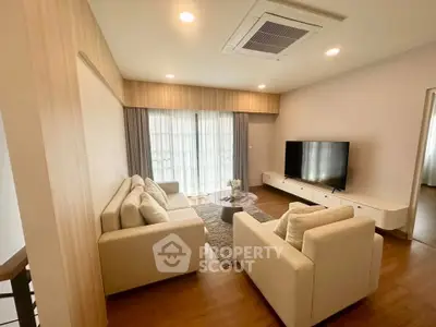 Spacious modern living room with elegant furniture and large TV, perfect for relaxation and entertainment.