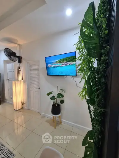 Modern living room with wall-mounted TV and lush green decor