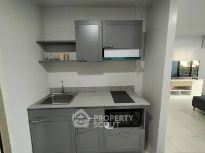 Modern compact kitchen with sleek gray cabinets and built-in appliances