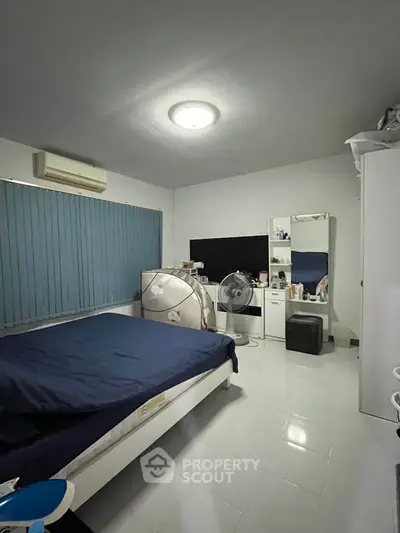 Spacious bedroom with modern furnishings and ample natural light, featuring a large bed and stylish decor.