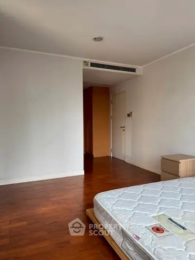 Spacious bedroom with wooden flooring and minimalist design