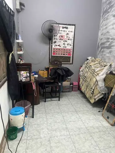 Cozy small room with tiled floor, wall fan, and cluttered storage space.