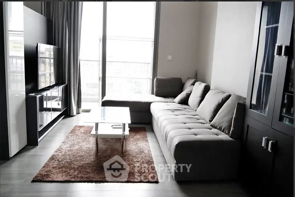 Modern living room with sleek furniture and large windows offering natural light.