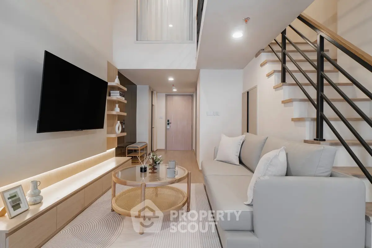 Modern living room with sleek design, featuring a cozy sofa, wall-mounted TV, and stylish staircase.