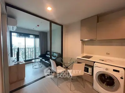 Modern apartment with open kitchen and living area featuring a washing machine and city view balcony.