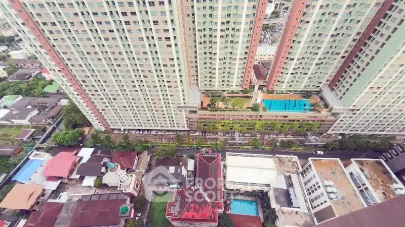Stunning aerial view of high-rise residential building with rooftop pool and lush surroundings.