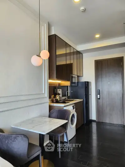 Modern kitchen with sleek appliances and cozy dining area in stylish apartment.