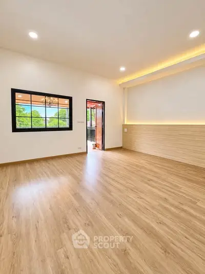 Spacious modern living room with wooden flooring and large window offering scenic views.