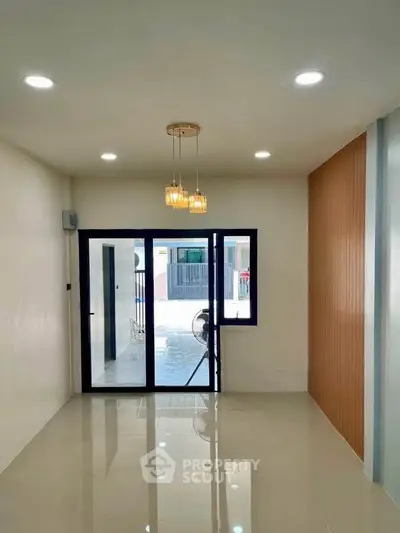 Modern living room with sleek lighting and large glass doors leading to a balcony.
