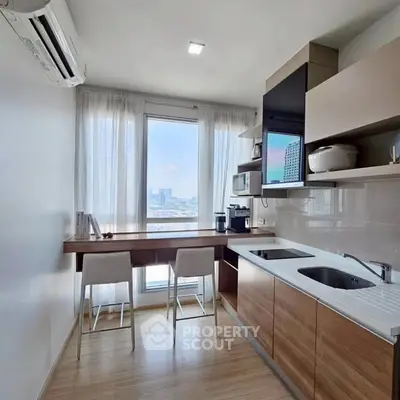 Modern kitchen with open layout and city view, featuring sleek cabinetry and natural light.