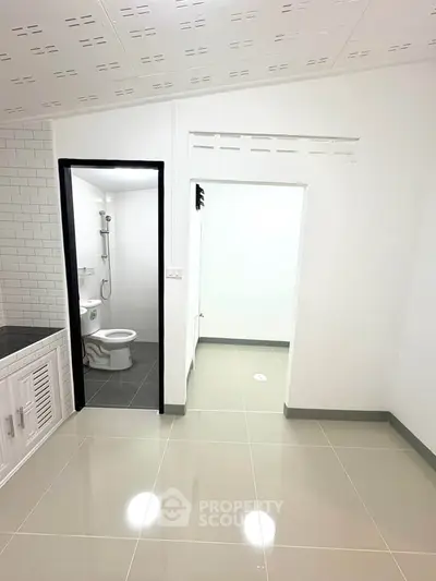 Modern minimalist bathroom with sleek tile flooring and white fixtures.