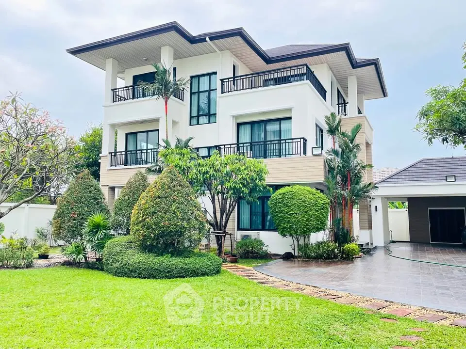 Stunning modern three-story house with lush garden and spacious driveway, perfect for luxurious living.