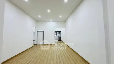 Spacious empty room with wooden flooring and bright lighting, ideal for customization.