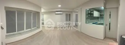 Spacious modern living room with open kitchen layout and large windows.